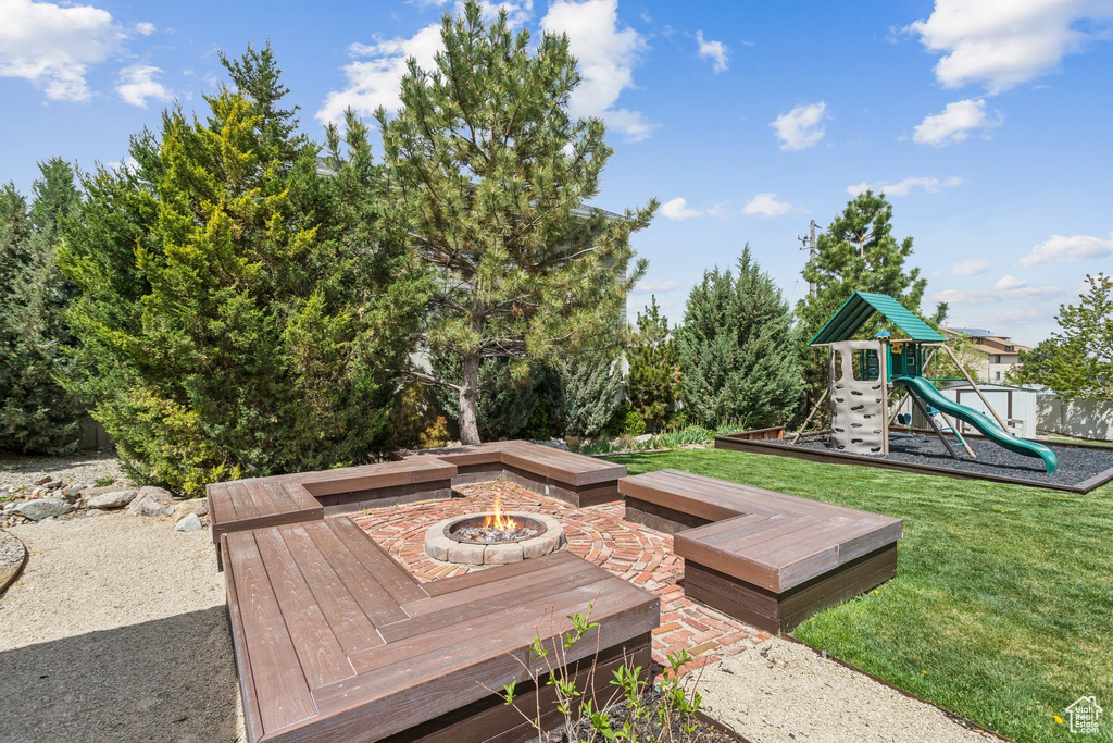 Deck with a playground, a fire pit, and a lawn