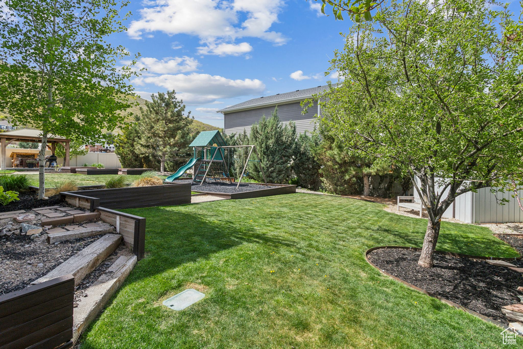 View of yard with a gazebo, a garden, a playground, and fence