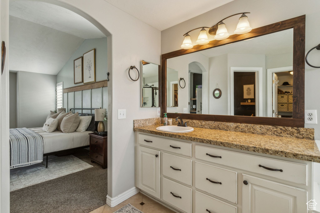Bathroom with vaulted ceiling, vanity, ensuite bathroom, and baseboards
