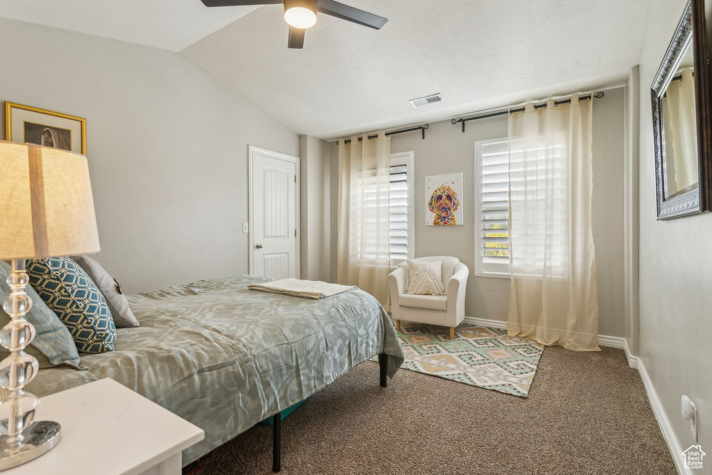 Carpeted bedroom featuring lofted ceiling, ceiling fan, baseboards, and visible vents
