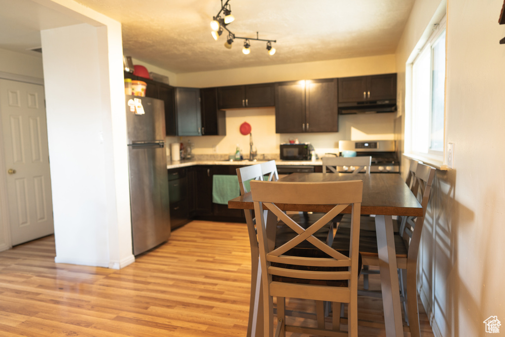 Kitchen with under cabinet range hood, light wood-style flooring, and black appliances
