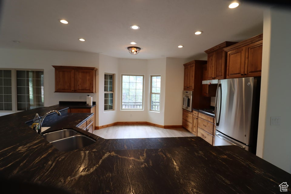Kitchen with a sink, stainless steel appliances, recessed lighting, baseboards, and light wood-style floors