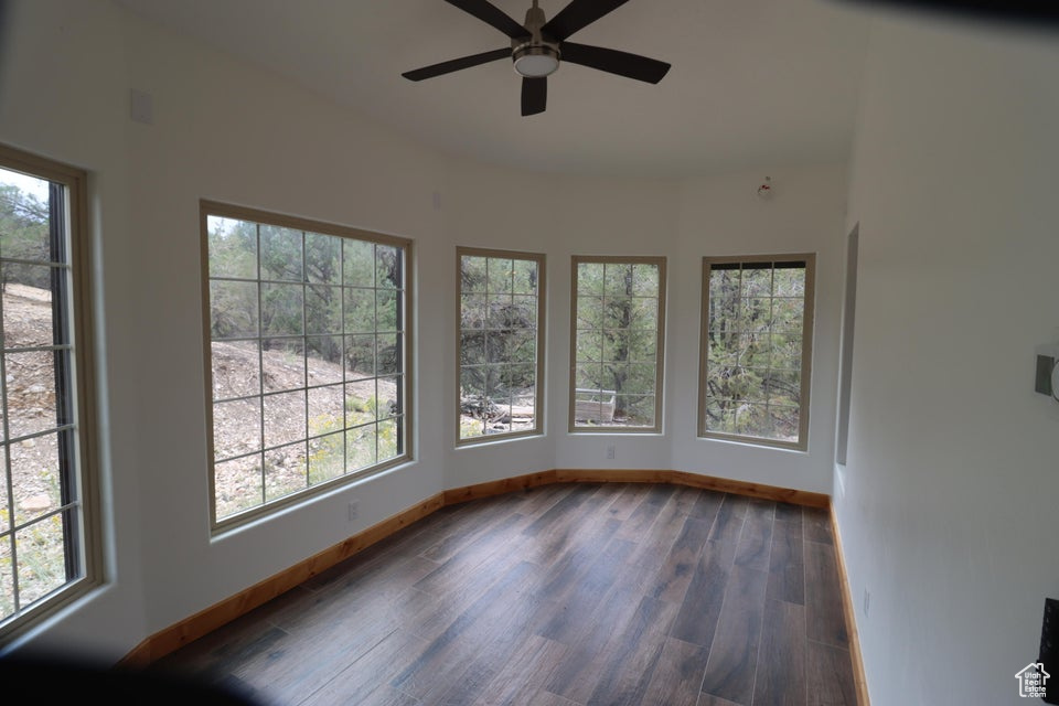 Unfurnished sunroom featuring a wealth of natural light, baseboards, and wood finished floors