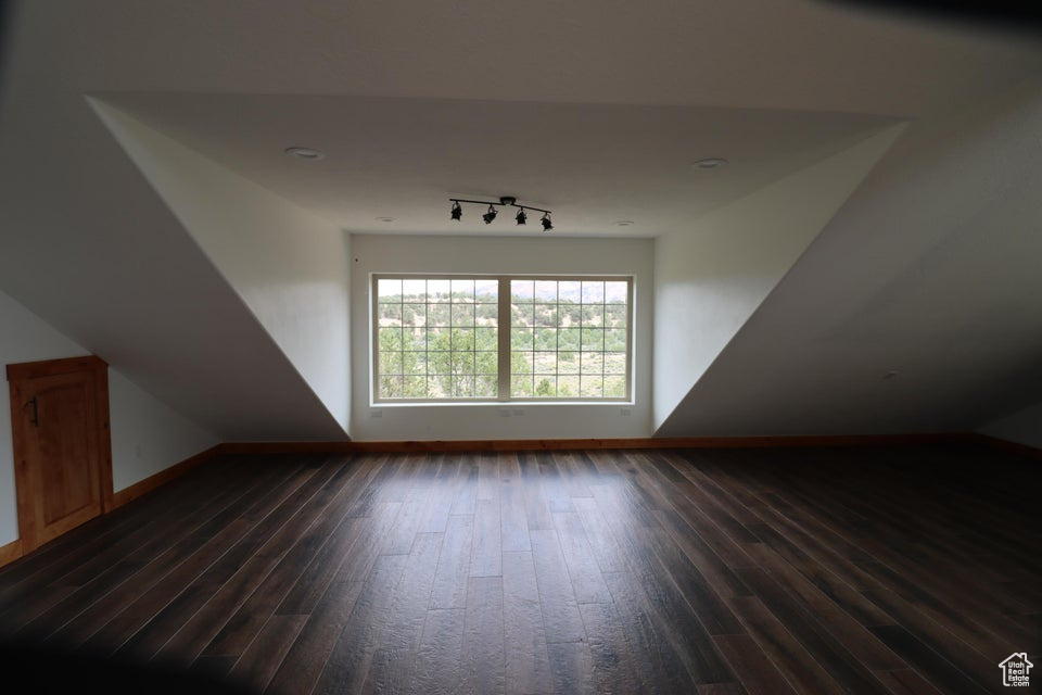 Bonus room featuring baseboards and dark wood-type flooring