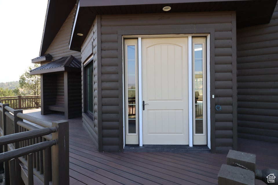 Doorway to property featuring log veneer siding and a wooden deck