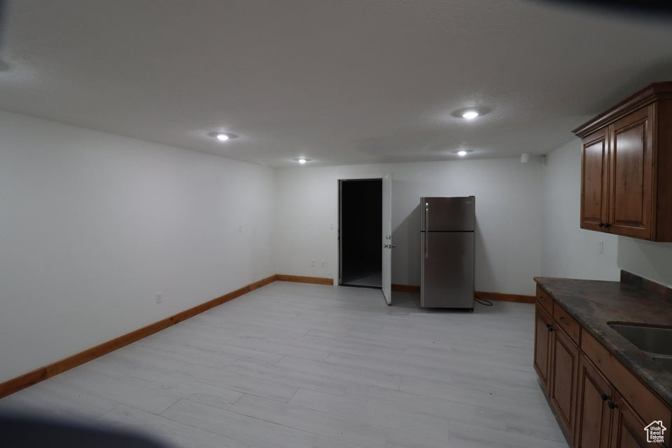 Kitchen with freestanding refrigerator, dark countertops, baseboards, and recessed lighting