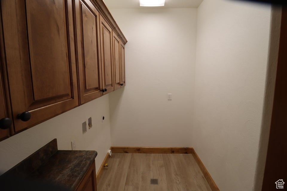 Washroom featuring baseboards, light wood-style floors, and cabinet space