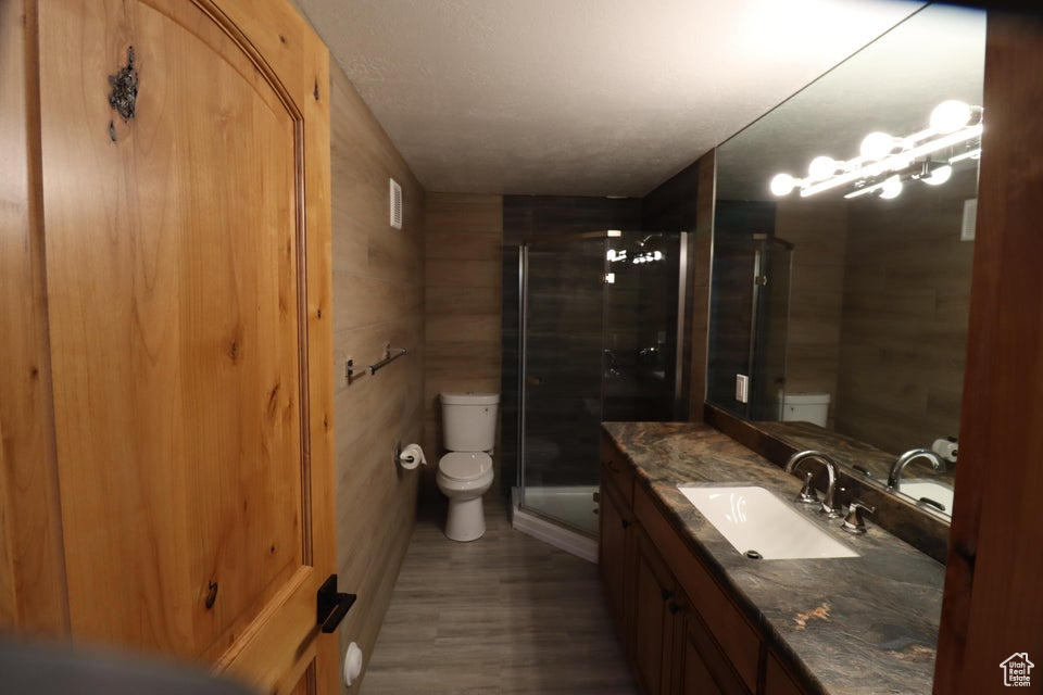 Bathroom with a stall shower, toilet, visible vents, vanity, and wood finished floors