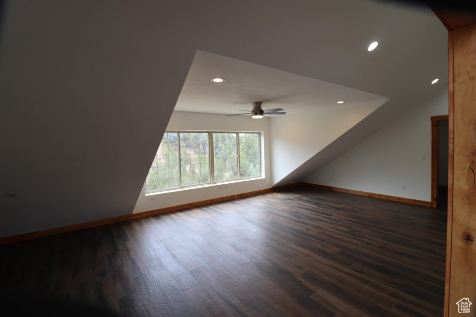 Additional living space with baseboards, dark wood-style flooring, and ceiling fan