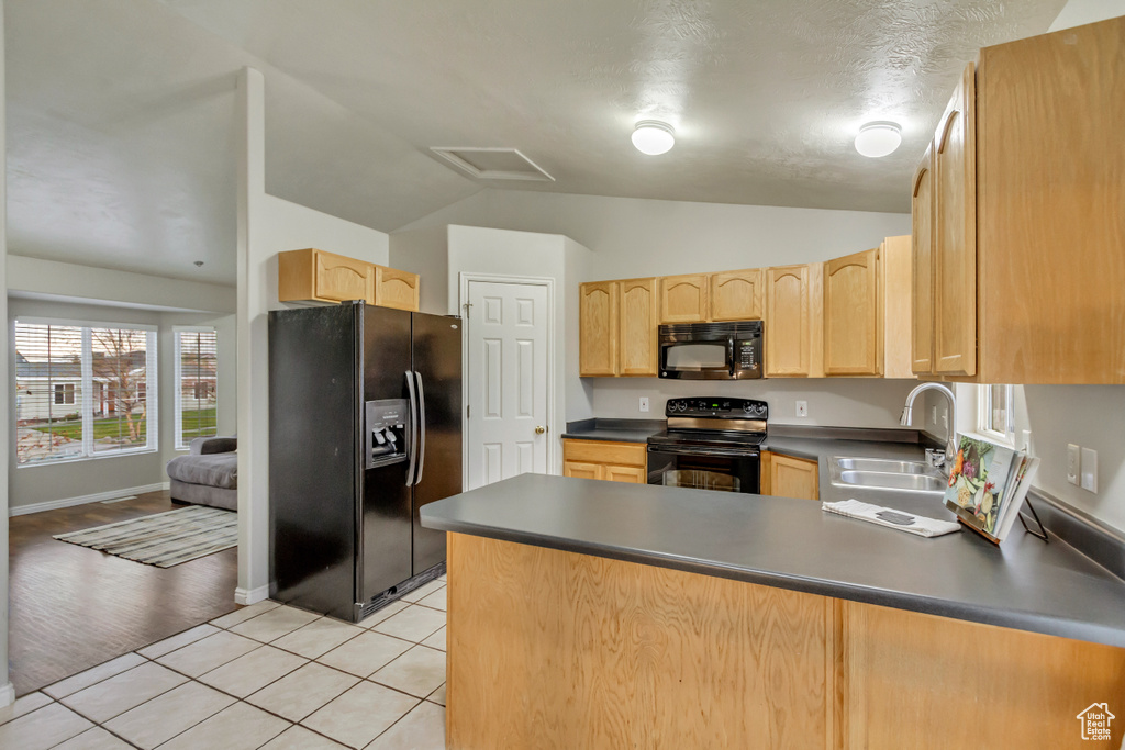 Kitchen with a sink, light brown cabinetry, black appliances, and dark countertops