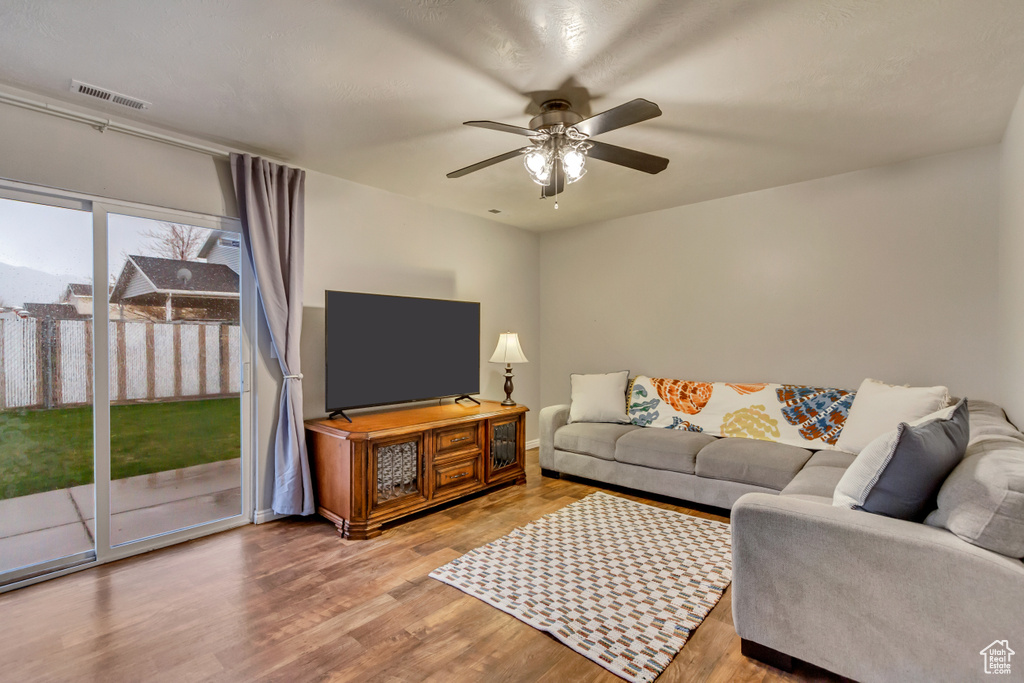 Living area featuring a ceiling fan, baseboards, visible vents, and wood finished floors