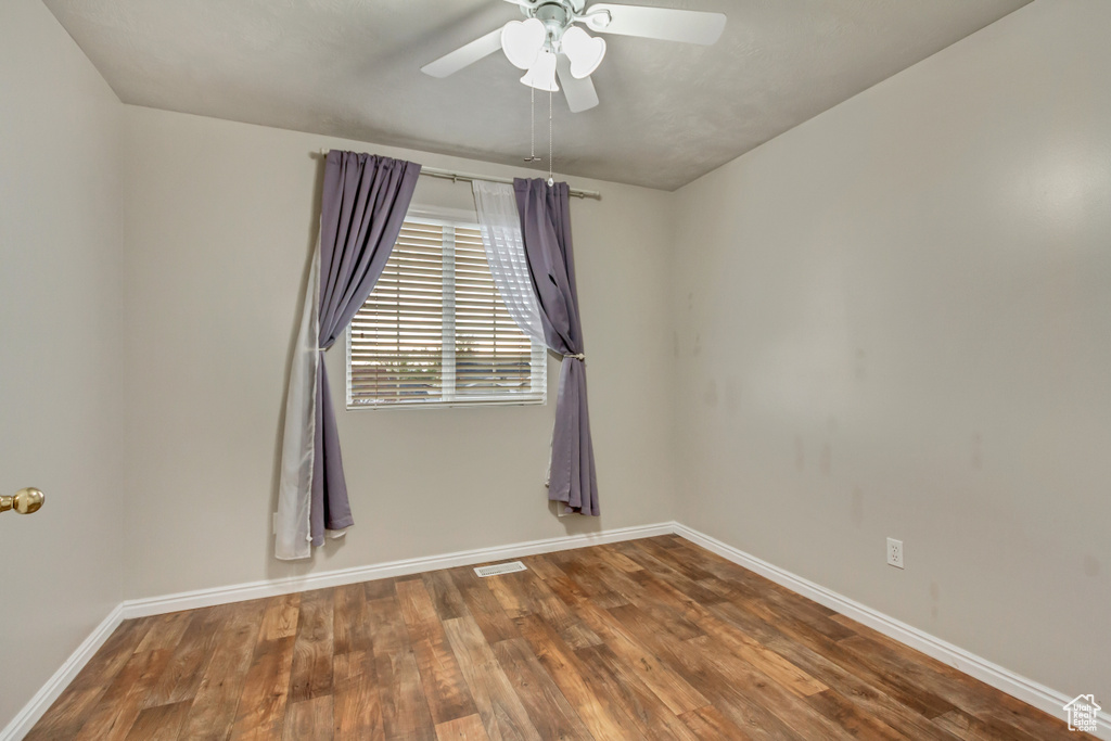 Unfurnished room featuring a ceiling fan, baseboards, and wood finished floors