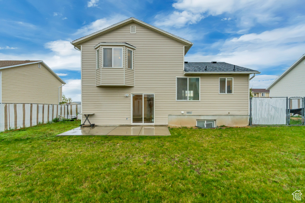 Rear view of property with a lawn, a patio, a fenced backyard, and roof with shingles