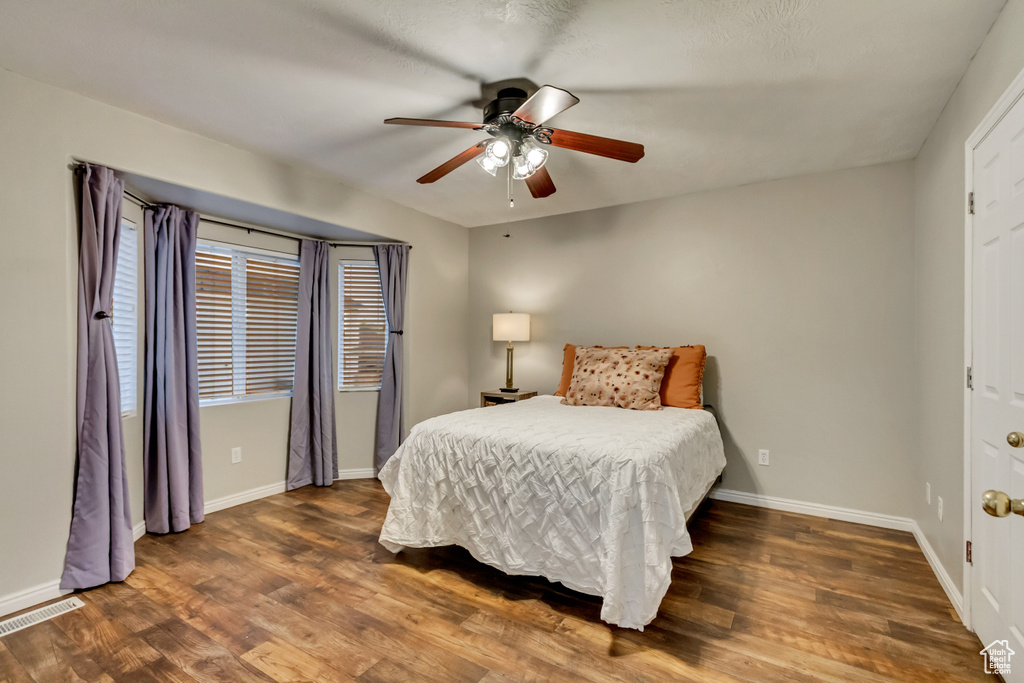 Bedroom featuring visible vents, a ceiling fan, baseboards, and wood finished floors