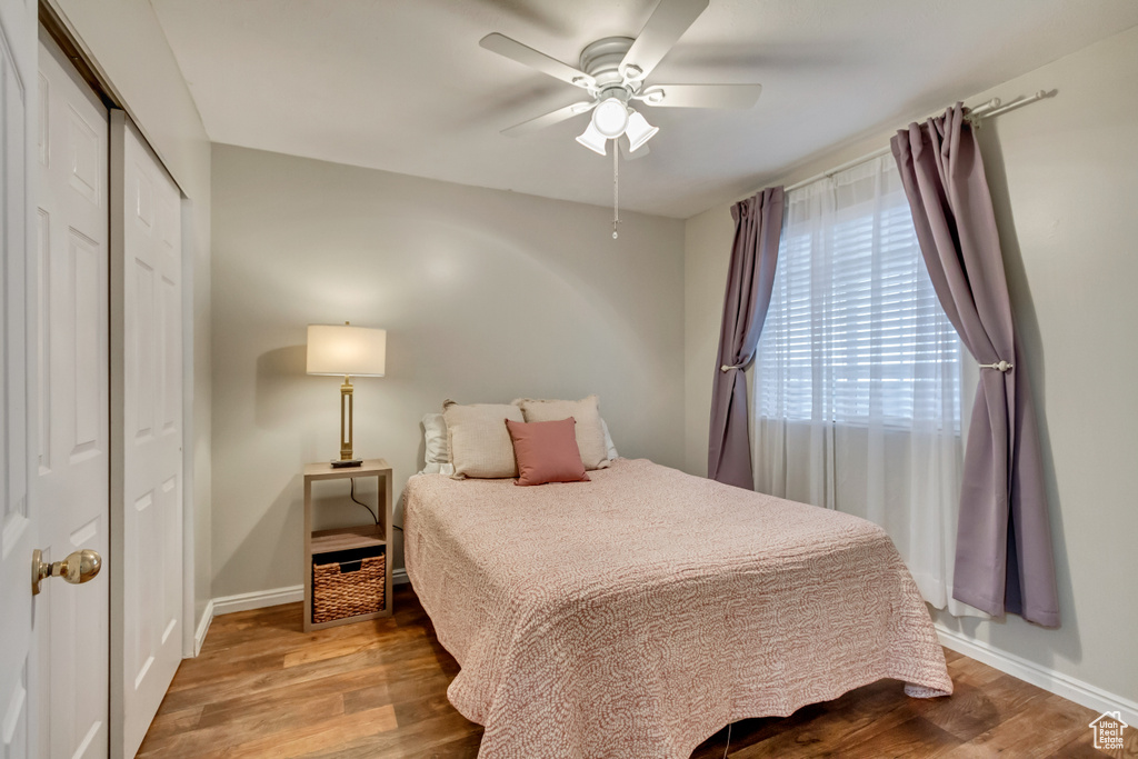 Bedroom featuring a ceiling fan, baseboards, wood finished floors, and a closet