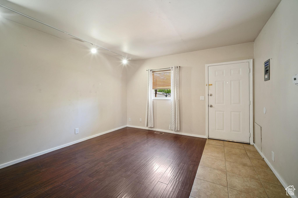Empty room featuring baseboards, wood finished floors, visible vents, and track lighting