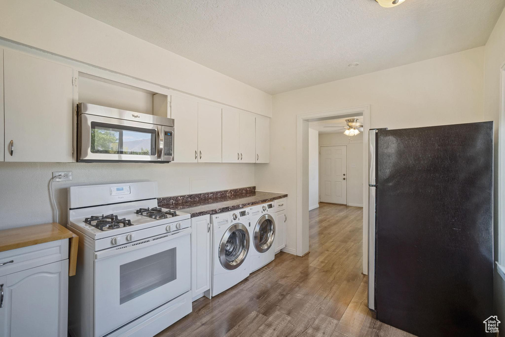 Kitchen with white cabinetry, washing machine and dryer, appliances with stainless steel finishes, and wood finished floors