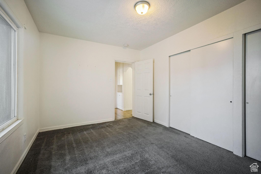 Unfurnished bedroom featuring a textured ceiling, baseboards, and carpet floors
