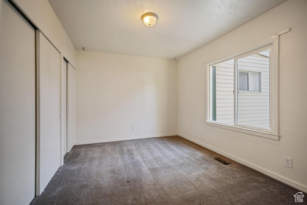 Unfurnished bedroom featuring carpet flooring, a closet, visible vents, and baseboards