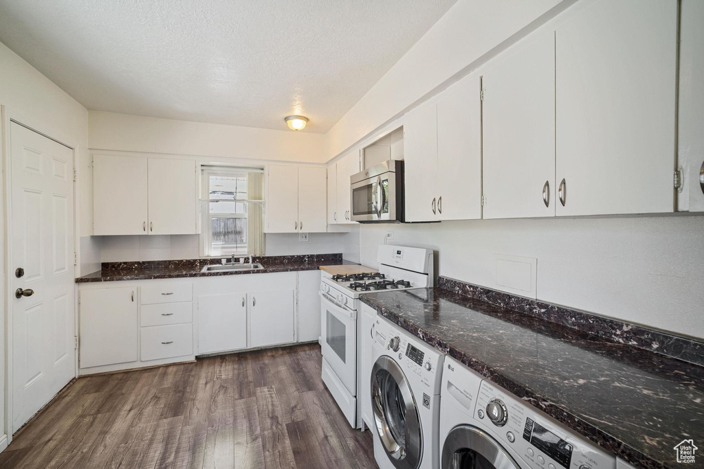 Laundry room featuring a sink, washer and clothes dryer, laundry area, a textured ceiling, and dark wood finished floors