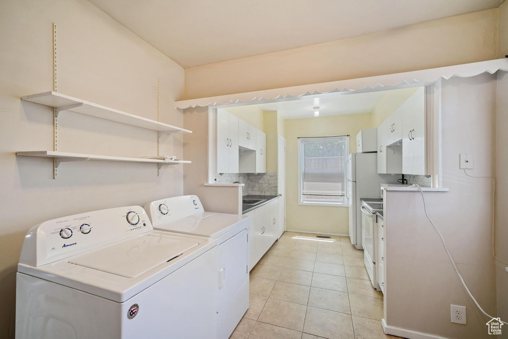 Clothes washing area with light tile patterned floors, laundry area, and separate washer and dryer