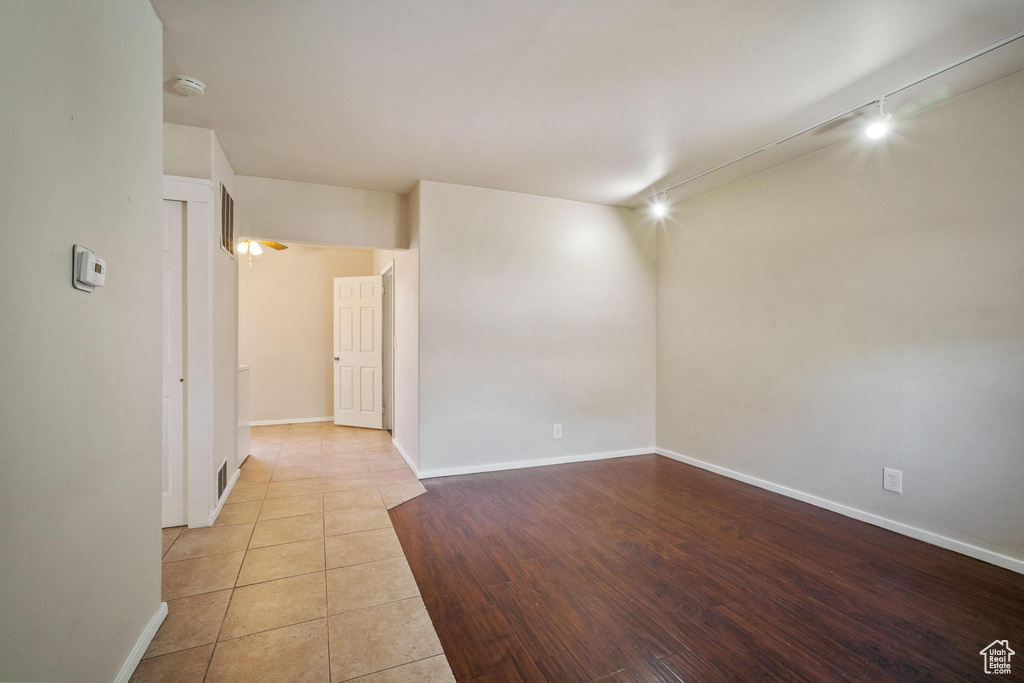 Tiled spare room featuring rail lighting and baseboards