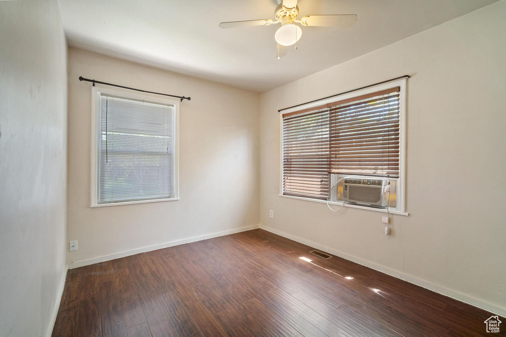 Spare room with baseboards, cooling unit, a ceiling fan, and wood finished floors