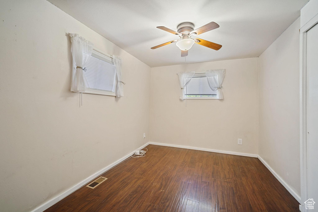 Empty room with baseboards, ceiling fan, visible vents, and wood finished floors