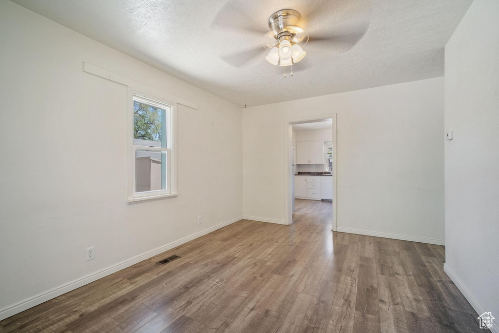 Spare room featuring a ceiling fan, baseboards, visible vents, and wood finished floors