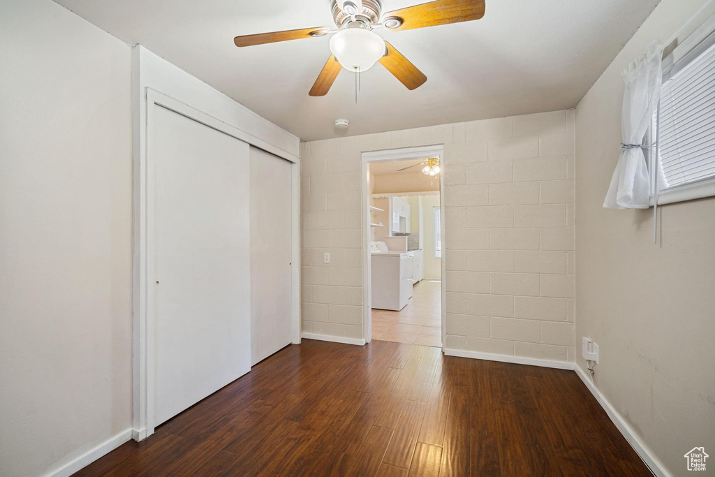 Unfurnished bedroom featuring washer / clothes dryer, a closet, baseboards, and wood finished floors