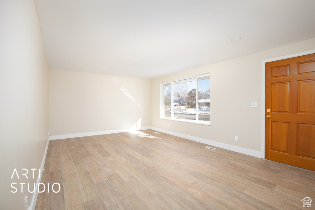 Empty room featuring light wood-style floors, visible vents, and baseboards
