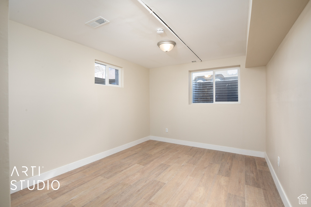Empty room with baseboards, light wood-style flooring, visible vents, and plenty of natural light