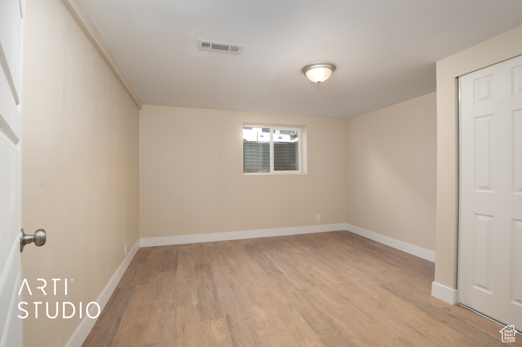 Empty room with visible vents, light wood-style flooring, and baseboards