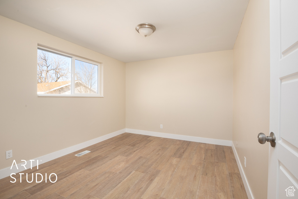 Unfurnished room featuring visible vents, light wood-style flooring, and baseboards