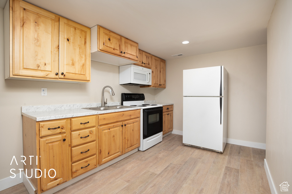 Kitchen featuring baseboards, white appliances, a sink, light countertops, and light wood-type flooring