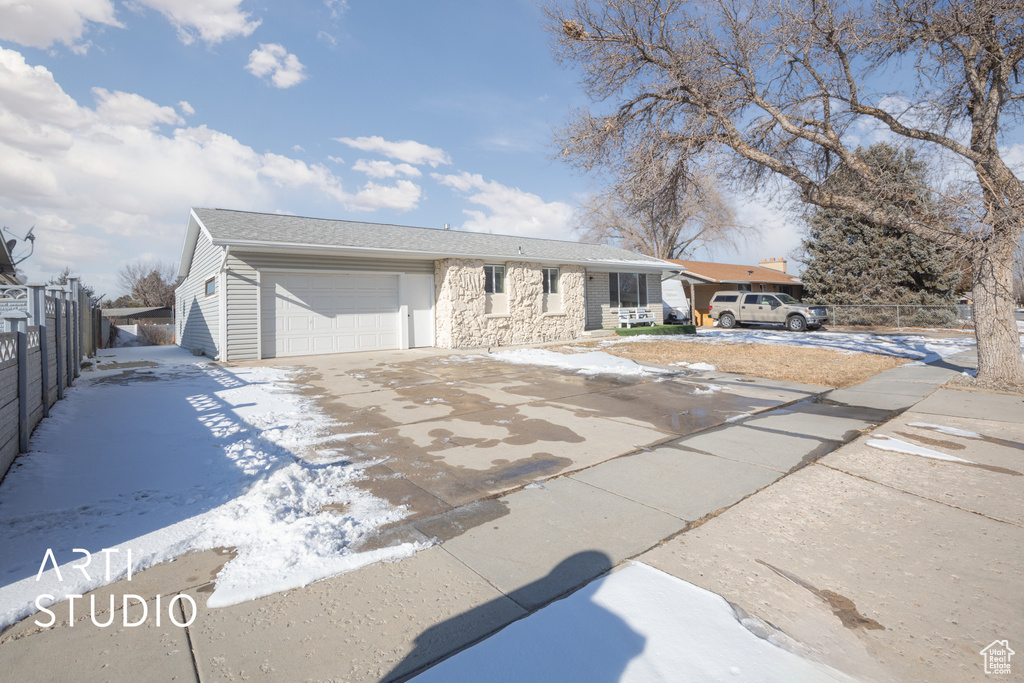Single story home with stone siding, fence, a garage, and concrete driveway