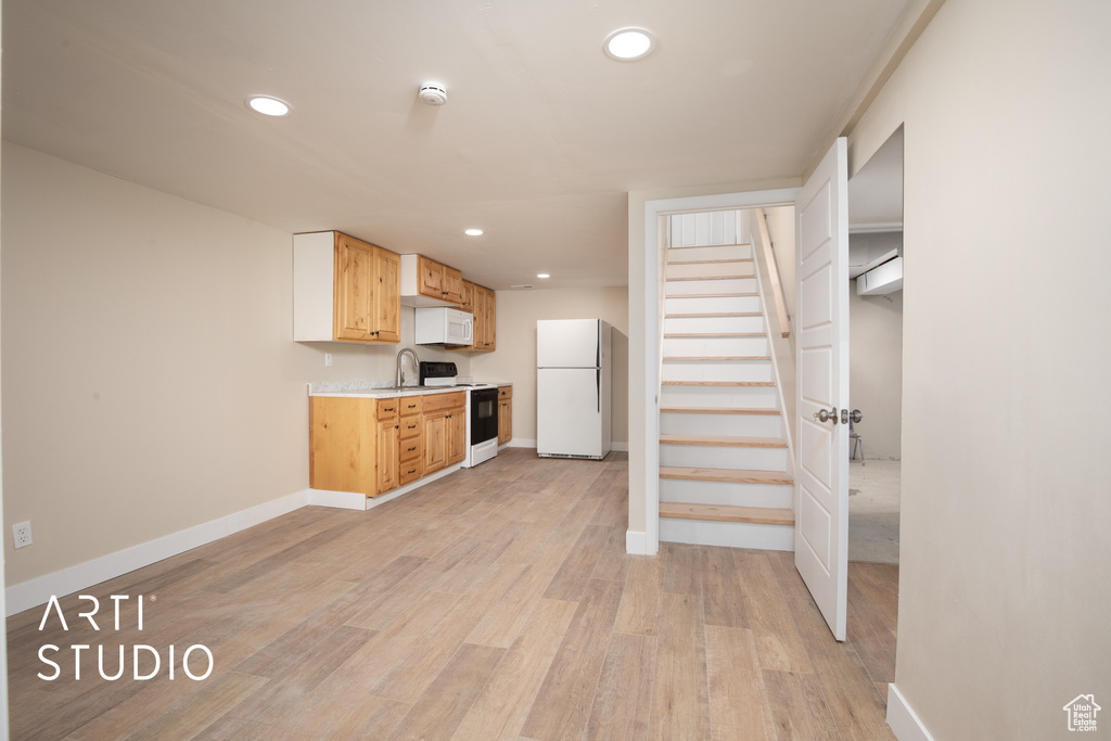 Kitchen with a sink, baseboards, white appliances, light countertops, and recessed lighting
