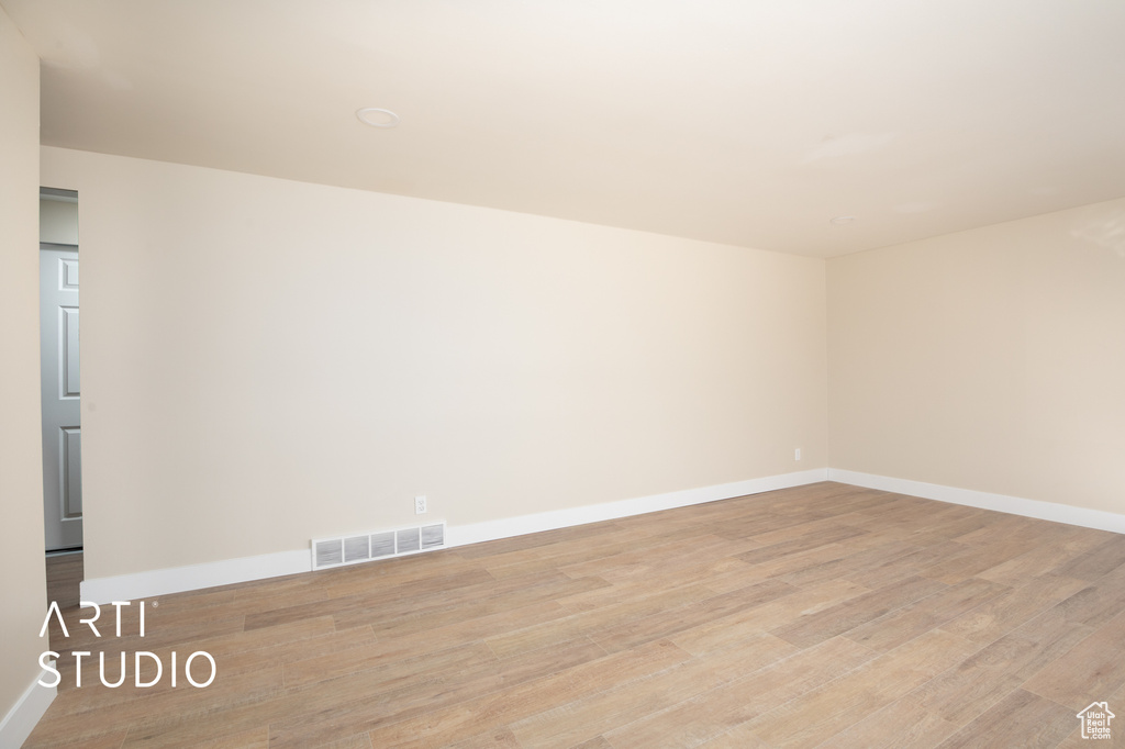Empty room featuring baseboards, light wood-type flooring, and visible vents