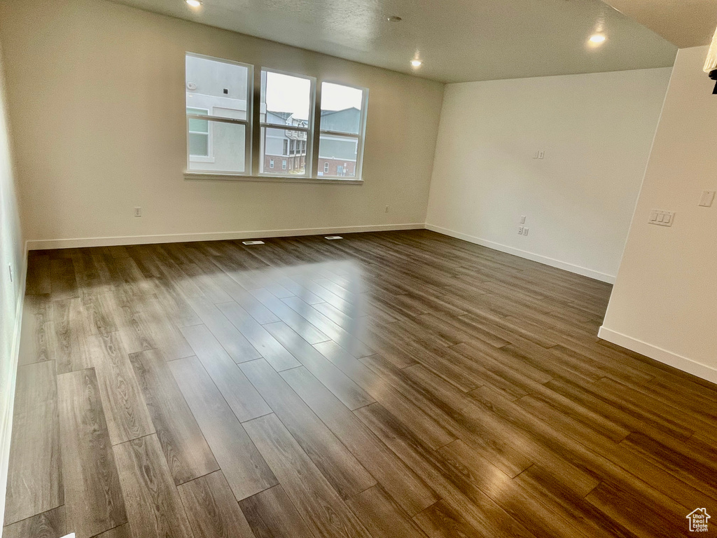 Spare room with baseboards, dark wood-style flooring, and recessed lighting