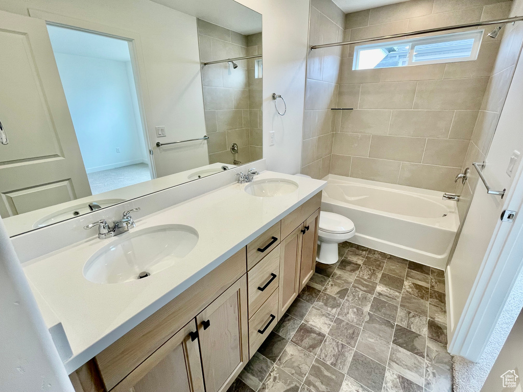 Bathroom featuring double vanity, toilet, shower / bath combination, and a sink