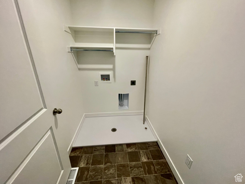 Laundry room featuring baseboards, hookup for a washing machine, stone finish flooring, hookup for an electric dryer, and laundry area
