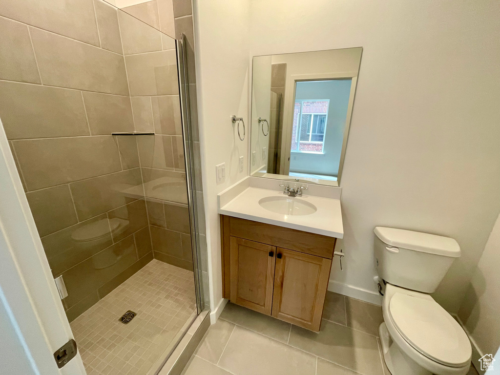 Bathroom featuring tile patterned floors, toilet, a stall shower, and vanity