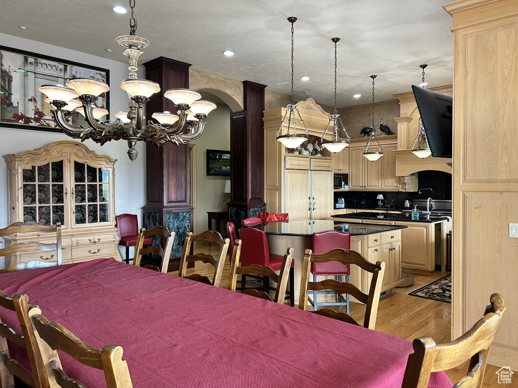 Dining room featuring an inviting chandelier, light wood-type flooring, arched walkways, and recessed lighting