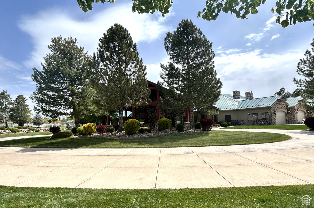 View of front of home featuring a chimney, stone siding, a front lawn, and metal roof