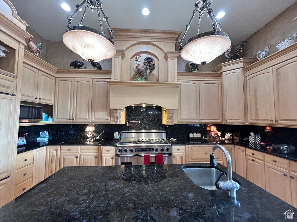 Kitchen featuring a sink, stainless steel appliances, light brown cabinets, and decorative backsplash