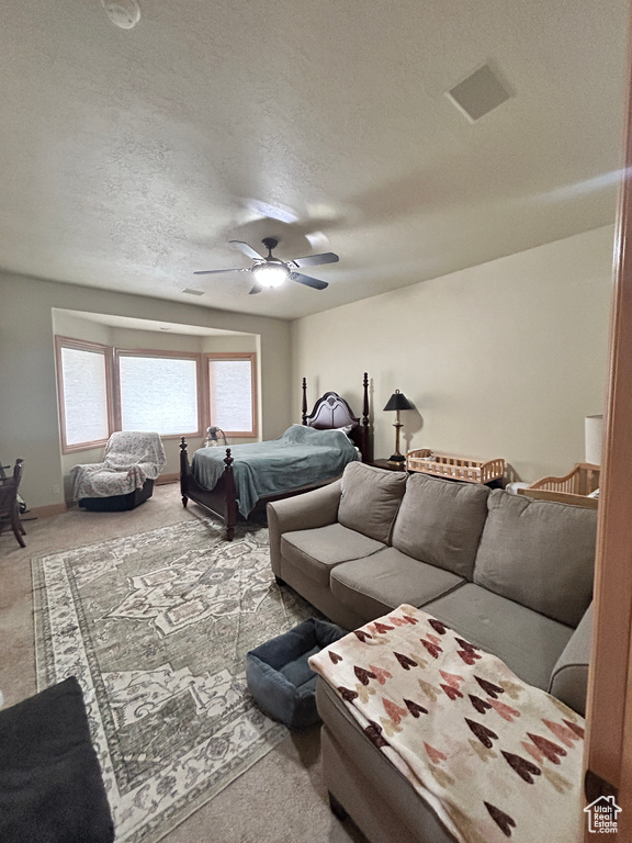 Carpeted bedroom with a textured ceiling, visible vents, and a ceiling fan