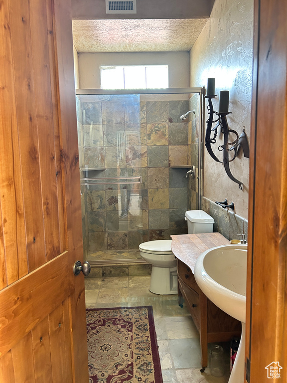 Bathroom featuring a stall shower, stone tile floors, toilet, visible vents, and vanity