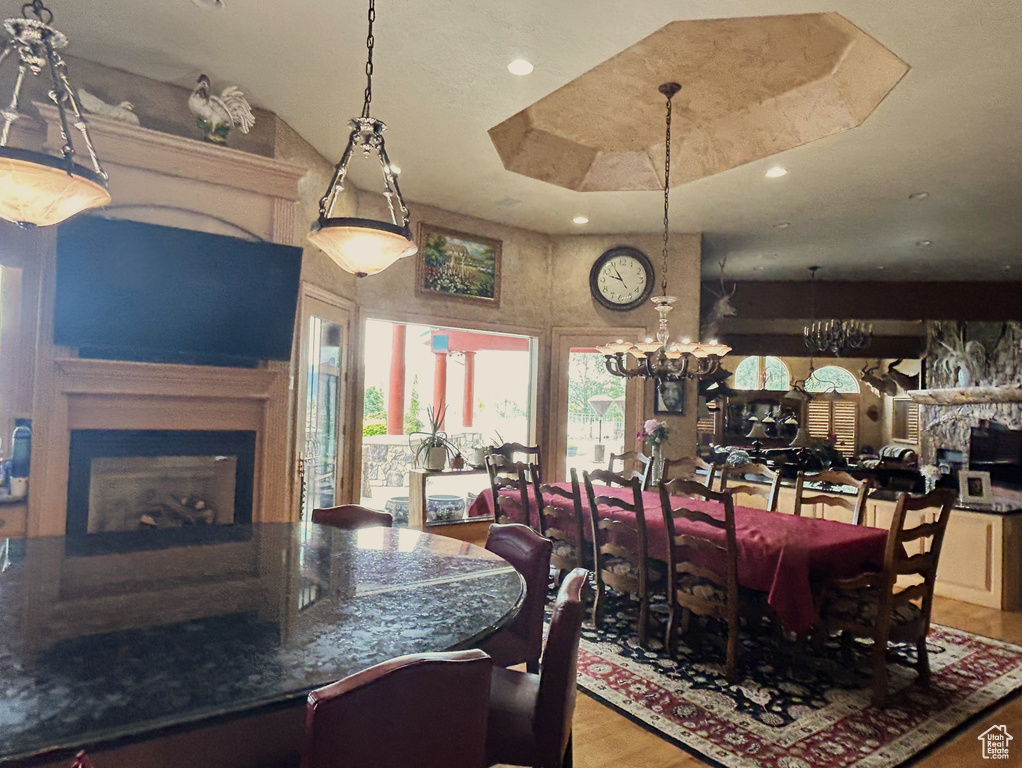 Dining area with a fireplace, a chandelier, wood finished floors, and recessed lighting