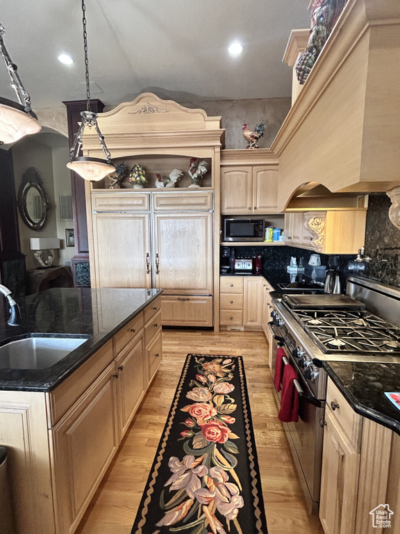 Kitchen featuring arched walkways, light wood finished floors, appliances with stainless steel finishes, and a sink