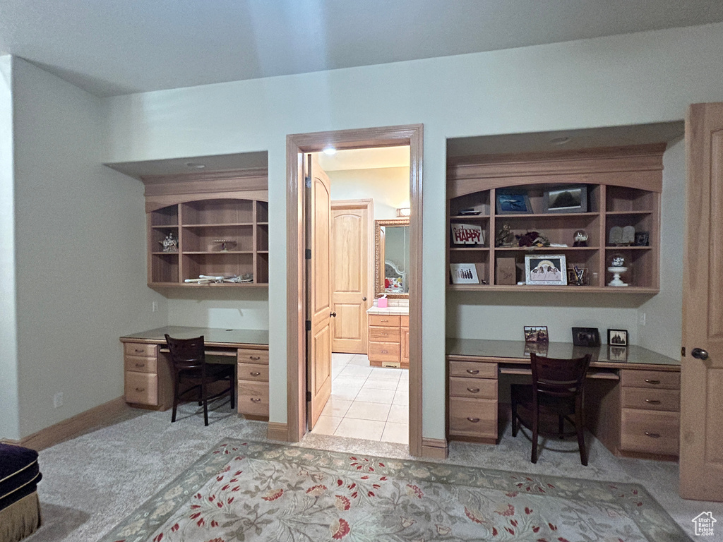 Office space featuring built in study area, light carpet, and baseboards